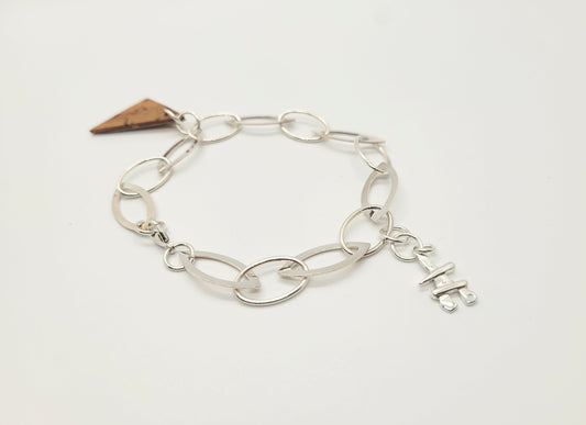 A sterling silver bracelet with an Inukshuk and birch bark pendant